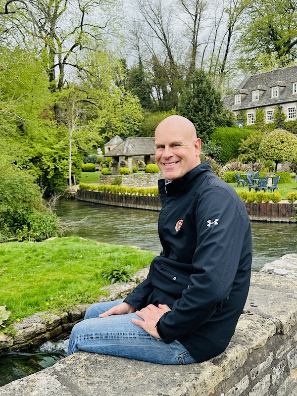 Jeffrey Rediger seated beside a river in the countryside